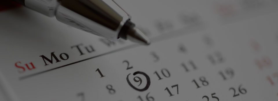 Pen marking date on calendar for schedule reminder.