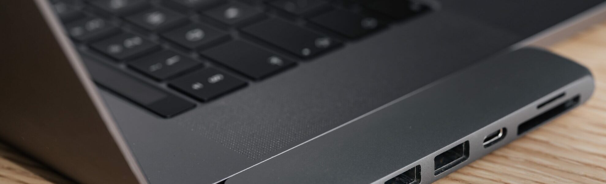 Close-up of laptop side with USB ports on wooden surface.
